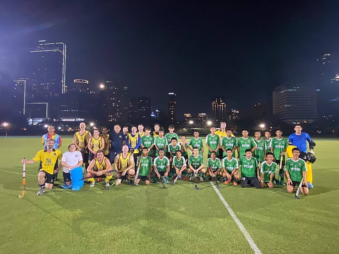 A group of people are posing for a picture on a field at night.