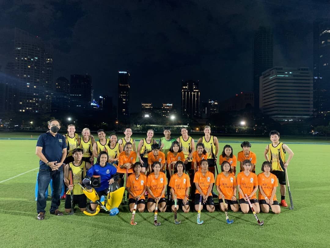 A group of people are posing for a picture on a field at night.