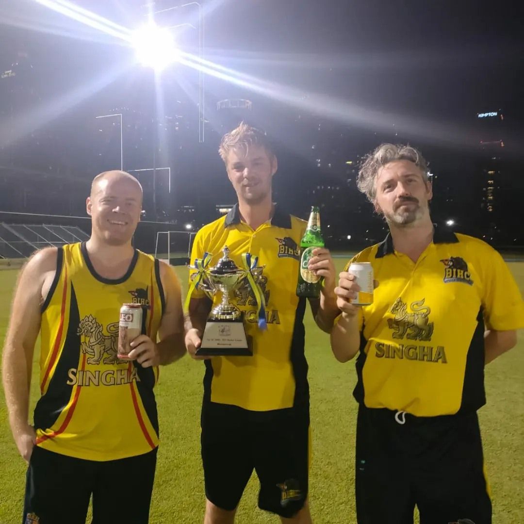 Three men in yellow singha shirts holding trophies