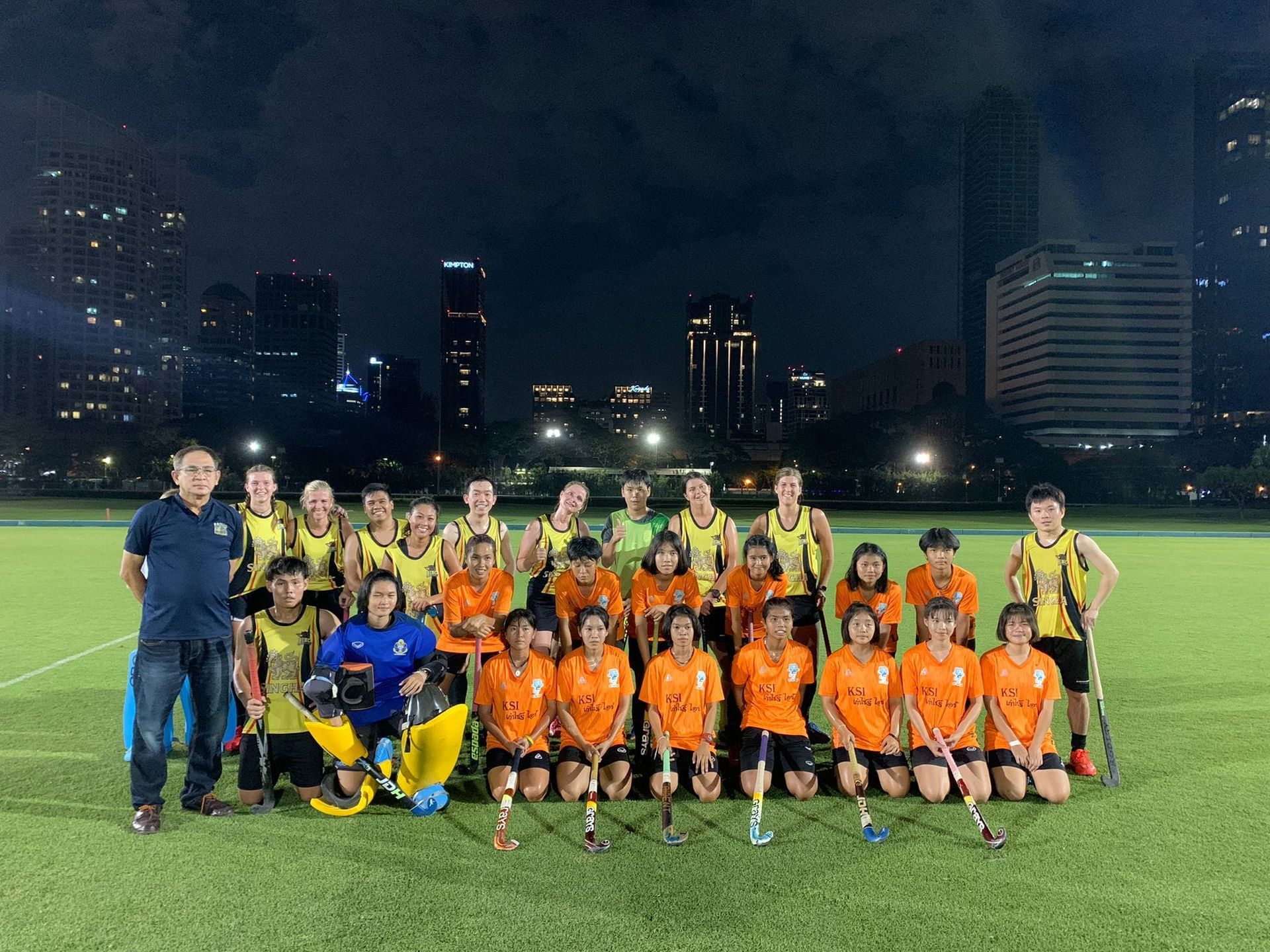 A group of people are posing for a picture on a field at night.