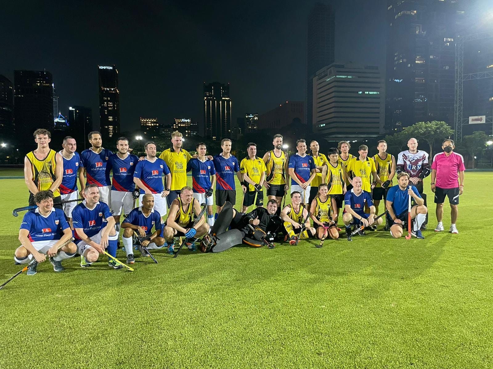 A group of soccer players are posing for a picture on a field at night.