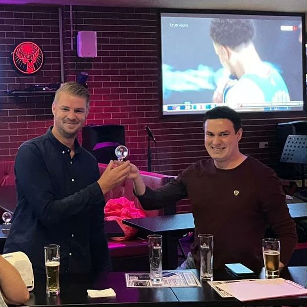 Two men toasting in front of a projector screen