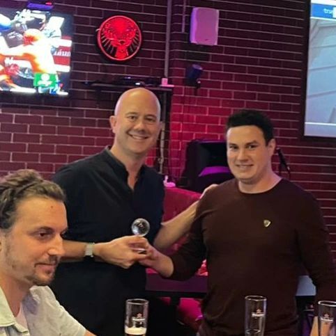 Three men are posing for a picture in front of a jagermeister sign