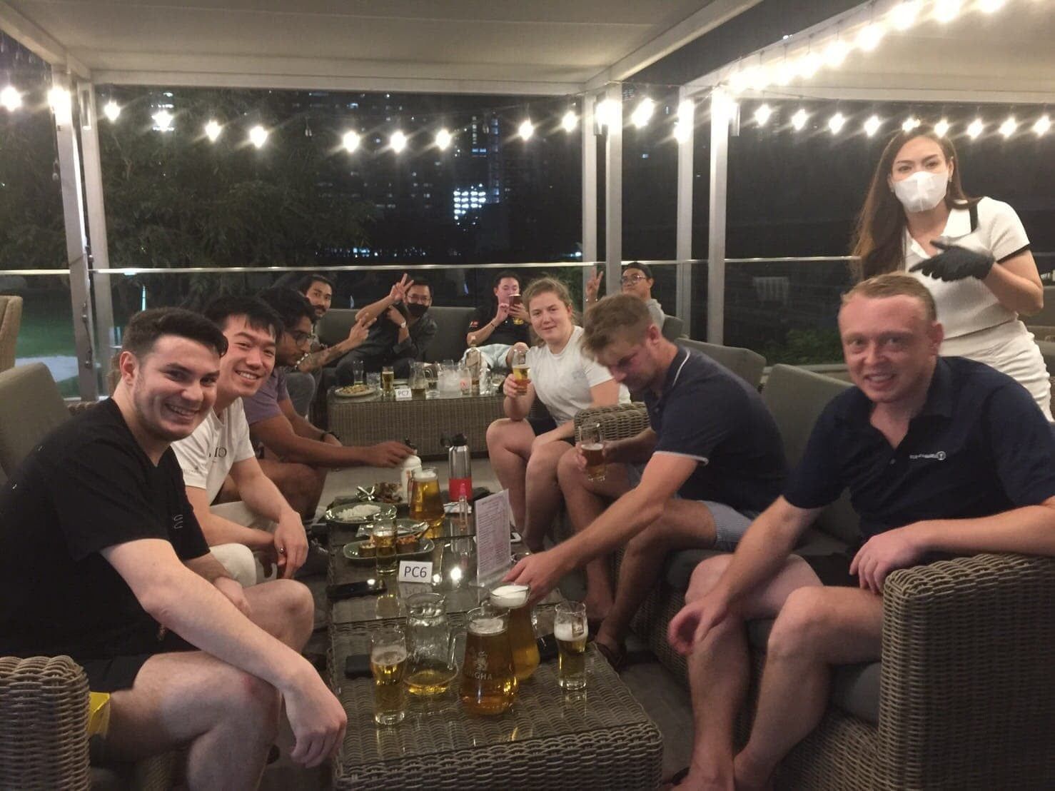 A group of people are sitting around a table with beer.