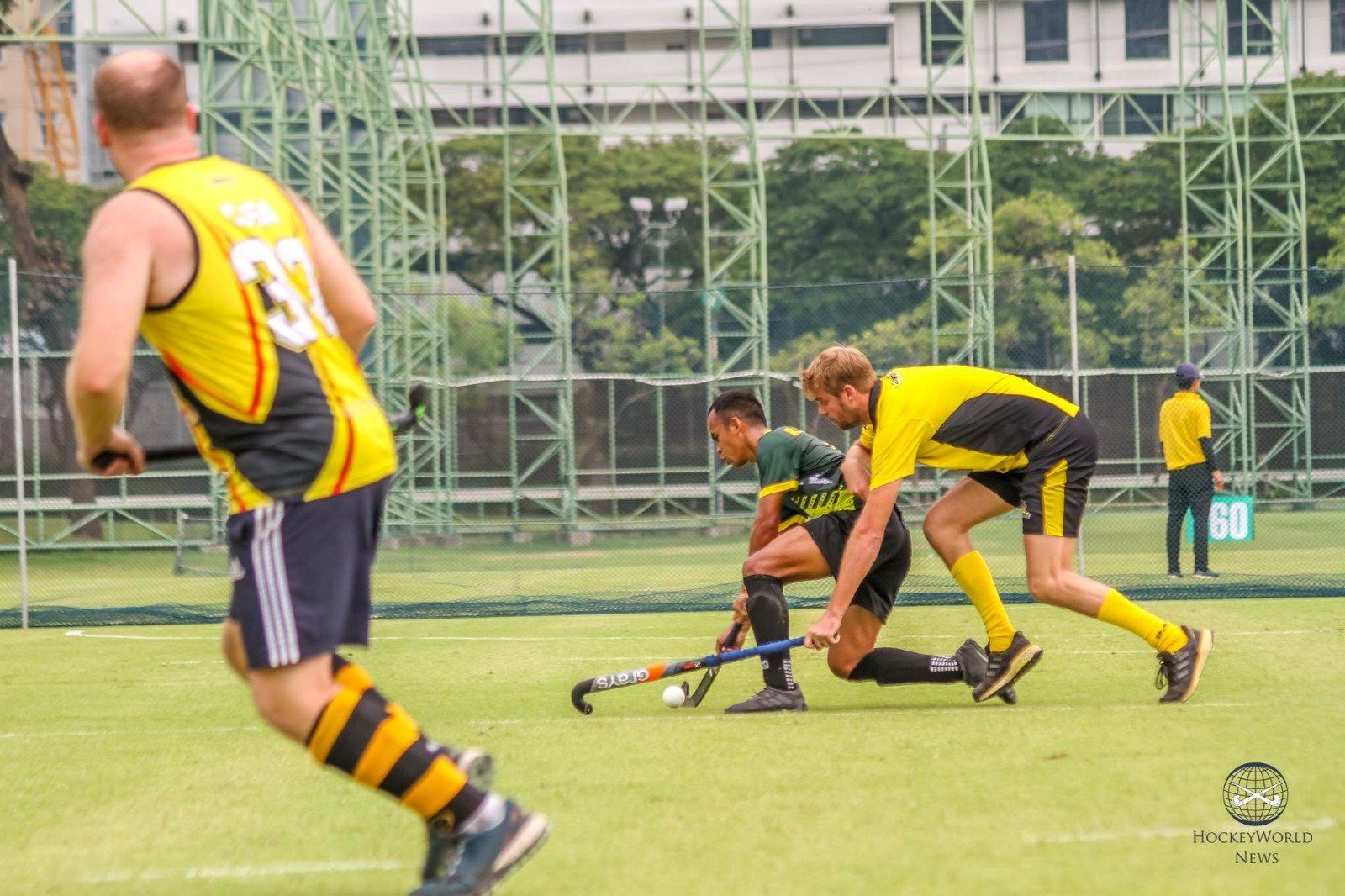 A group of men are playing field hockey on a field.