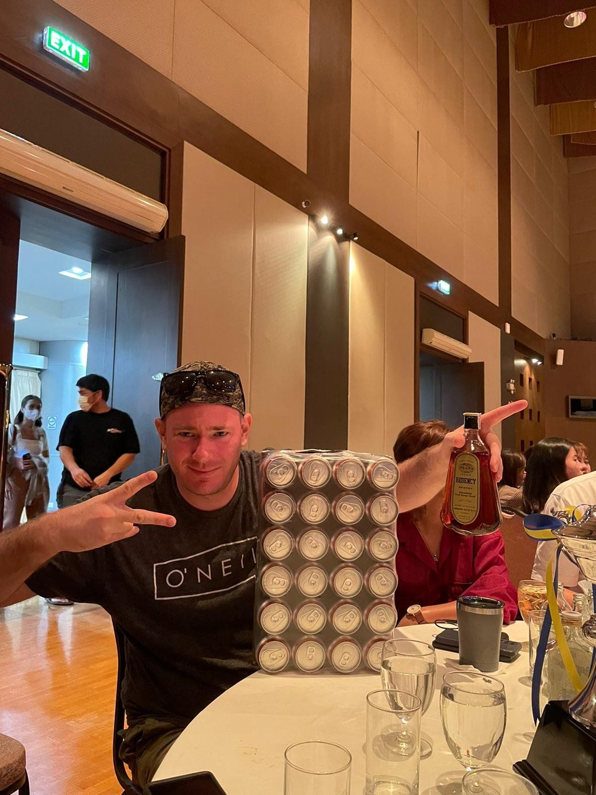 A man is sitting at a table holding a box of beer.