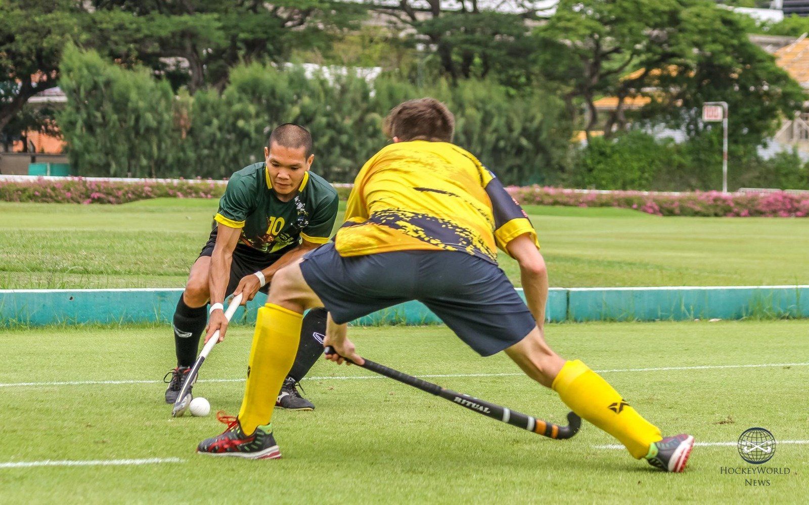 Two men are playing field hockey on a field.