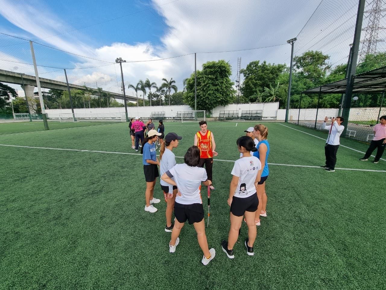 A group of people are standing in a circle on a soccer field.