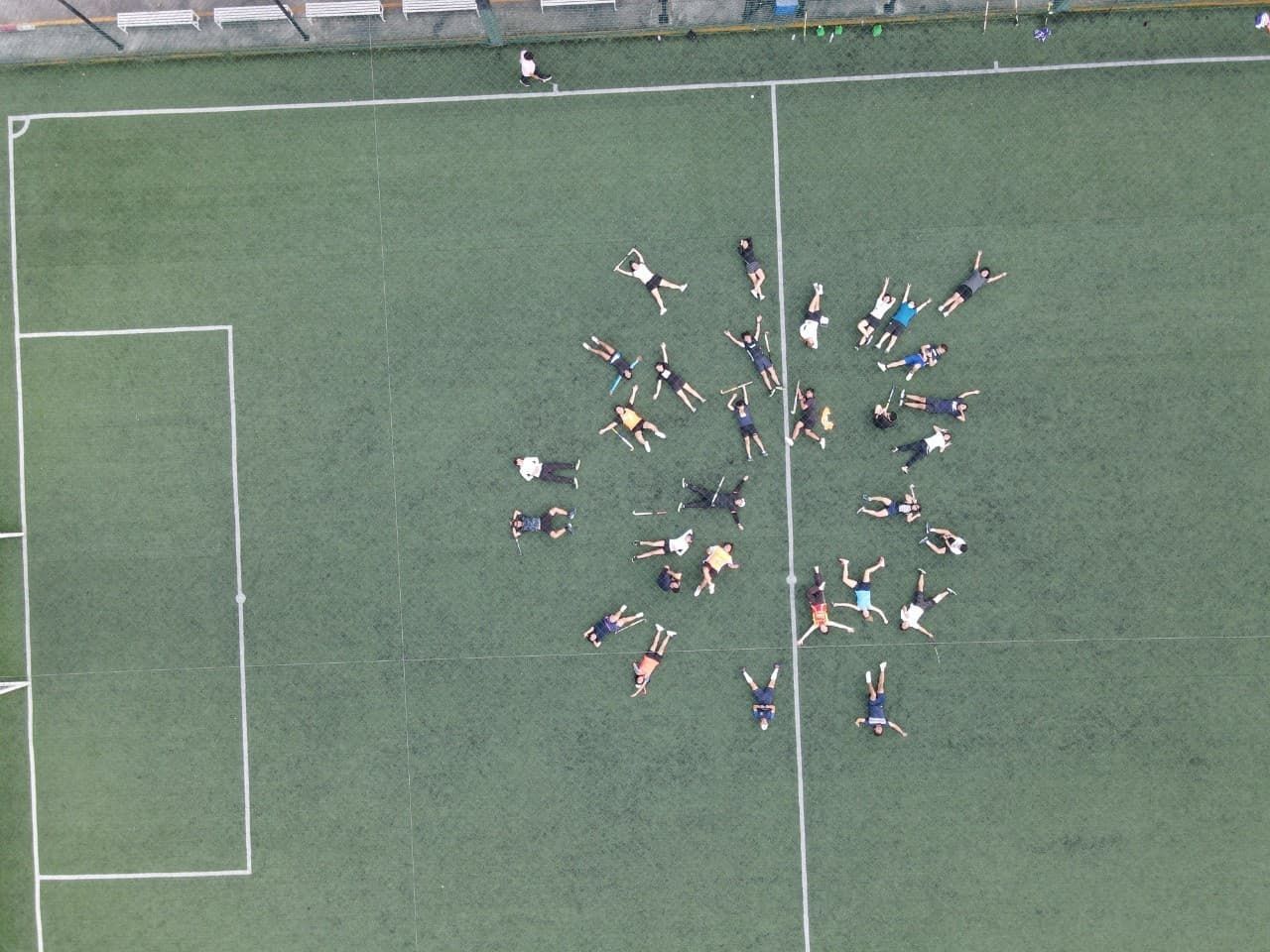 A group of people are laying in a circle on a soccer field