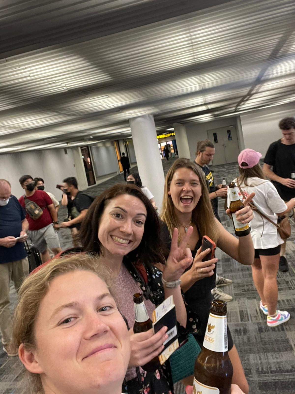 A group of people are standing around a table holding bottles of beer.