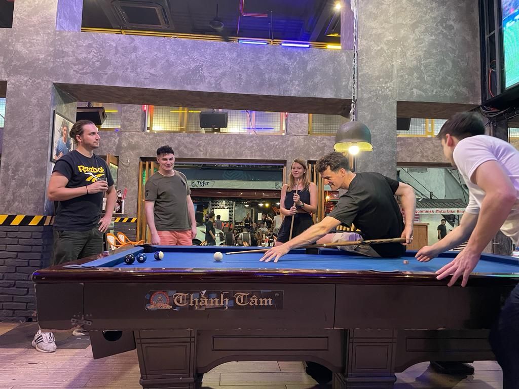 A group of men are playing pool in a bar.