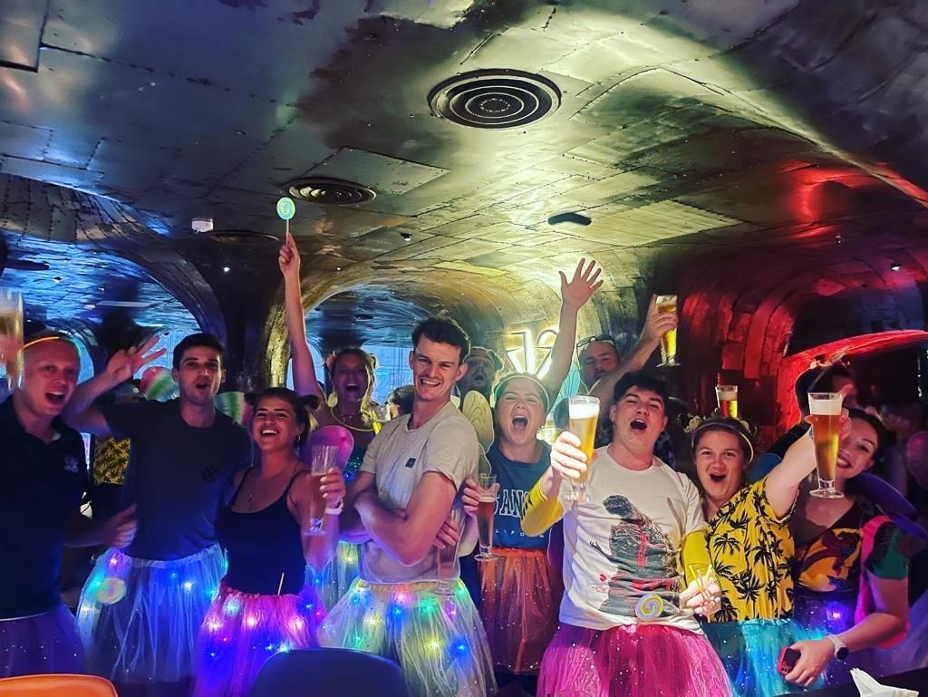 A group of people are standing in a room holding glasses of beer.