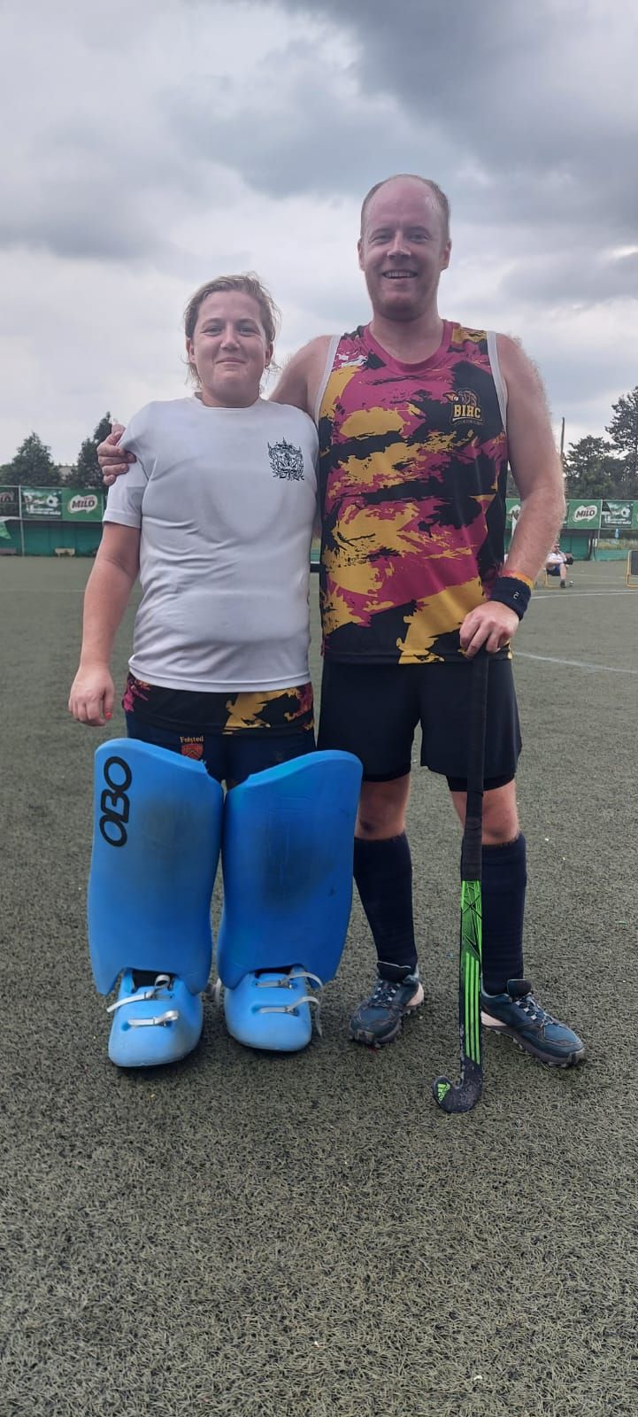 A man and a woman are standing next to each other on a field.