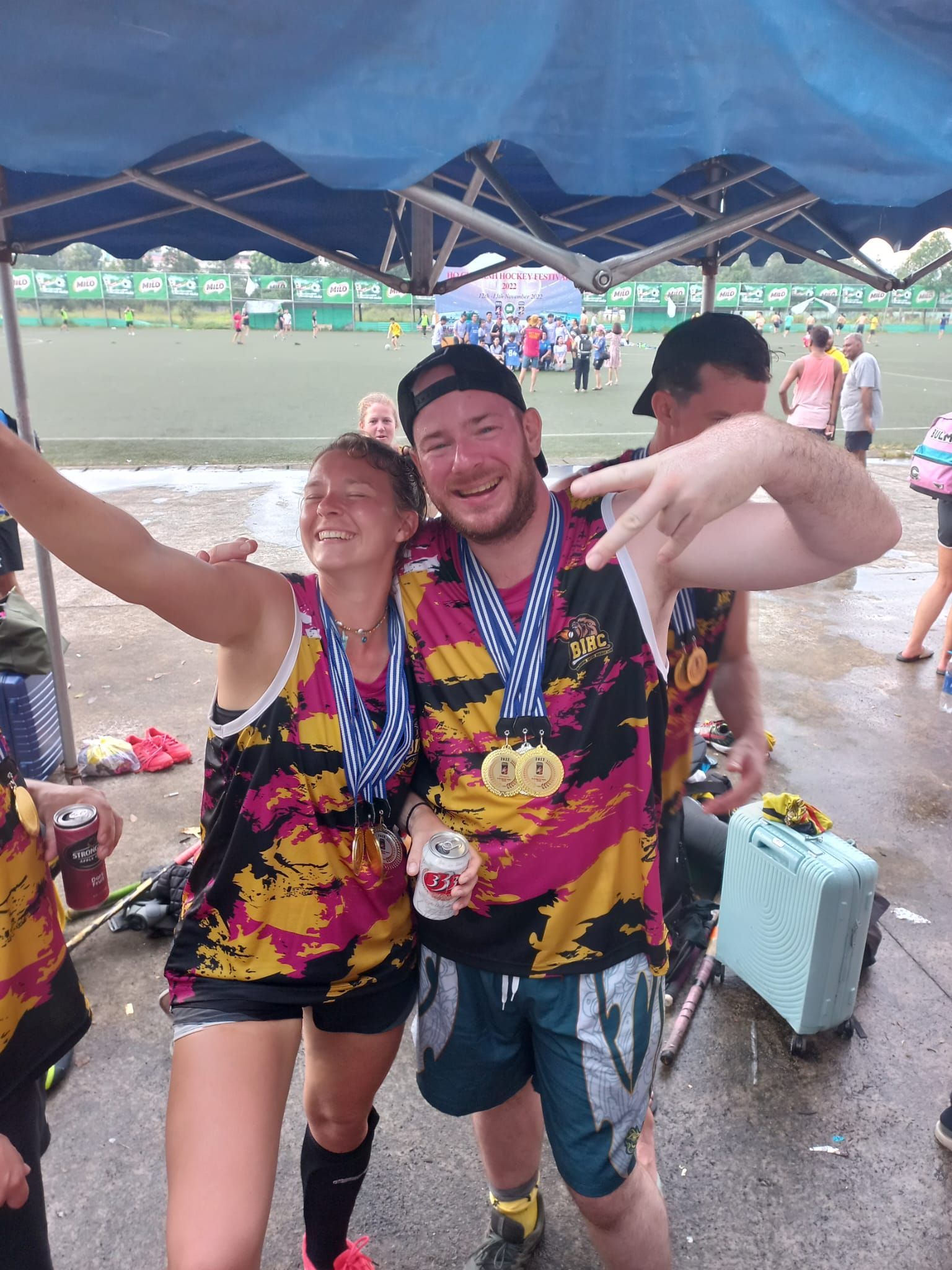 A man and a woman are posing for a picture under a tent.