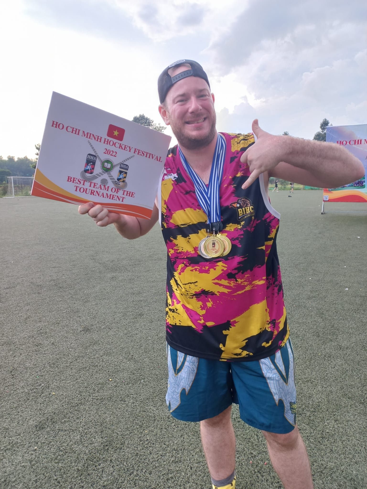 A man in a colorful shirt is holding a medal and a certificate.
