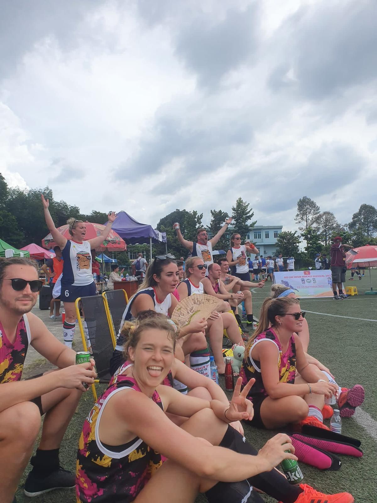 A group of people are sitting on the ground watching a game.