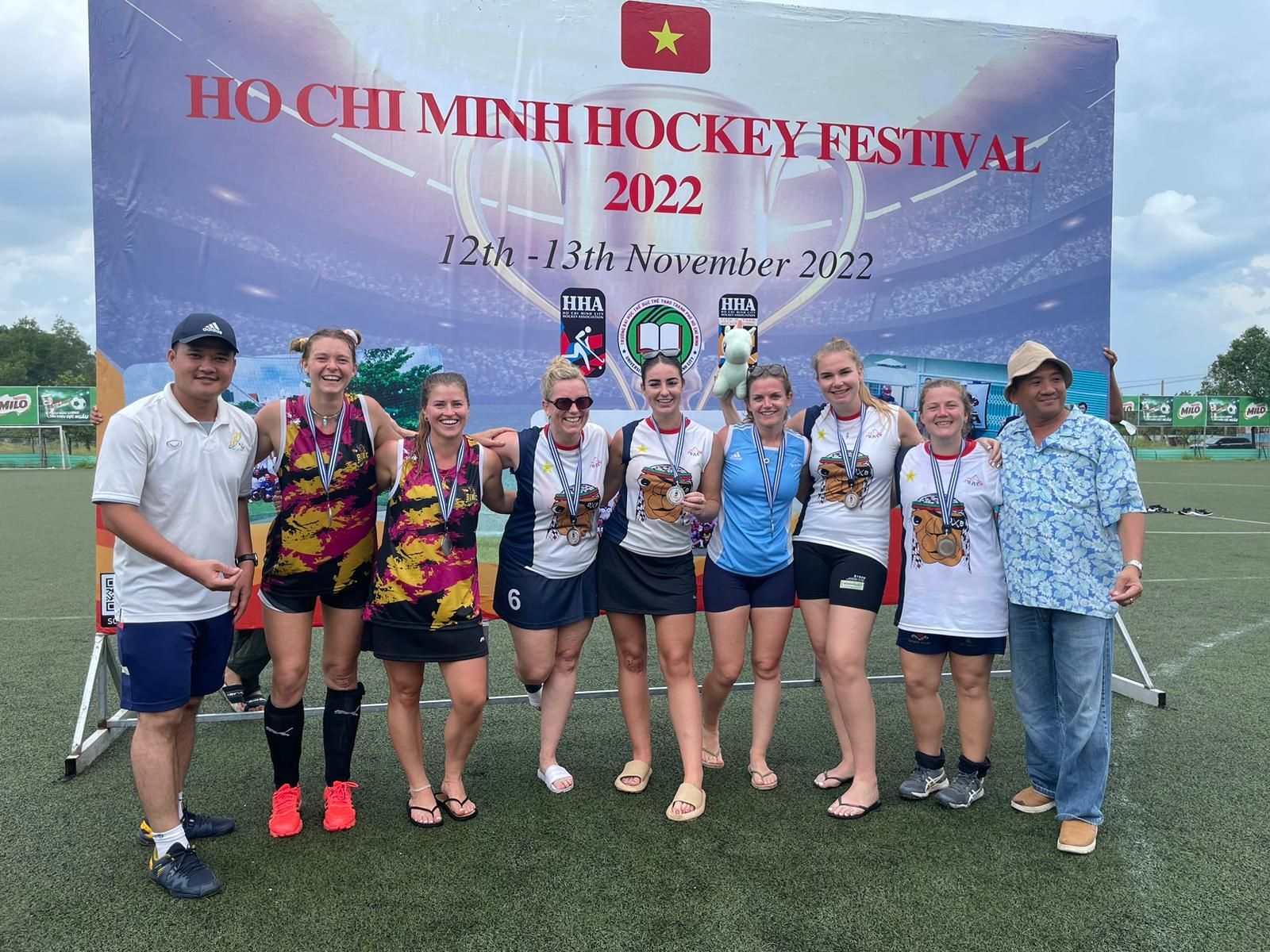 A group of people are posing for a picture in front of a sign that says hockey festival.