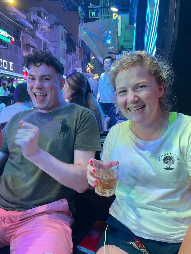 A man and a woman are sitting next to each other holding drinks.