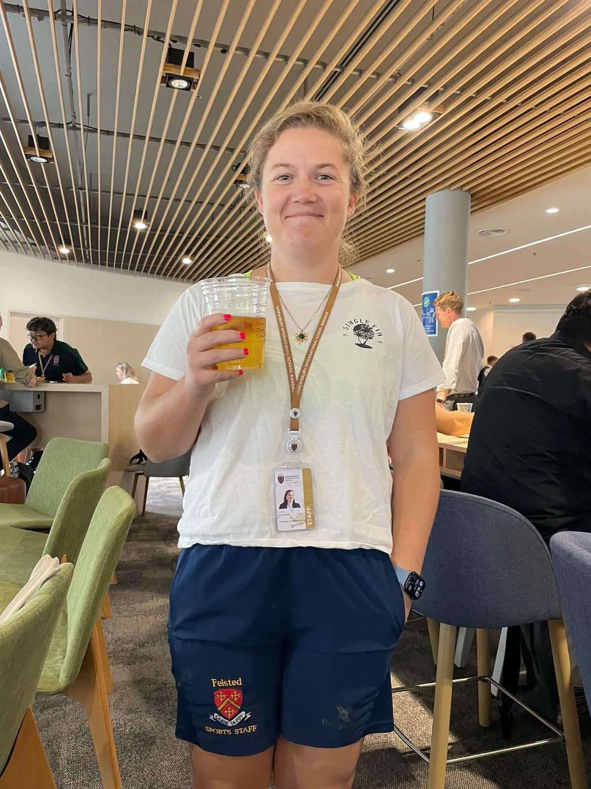 A woman is holding a glass of beer in a restaurant.