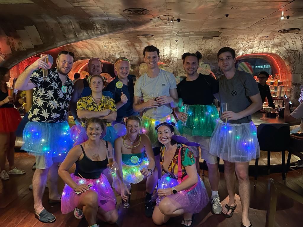 A group of people wearing light up skirts are posing for a picture.