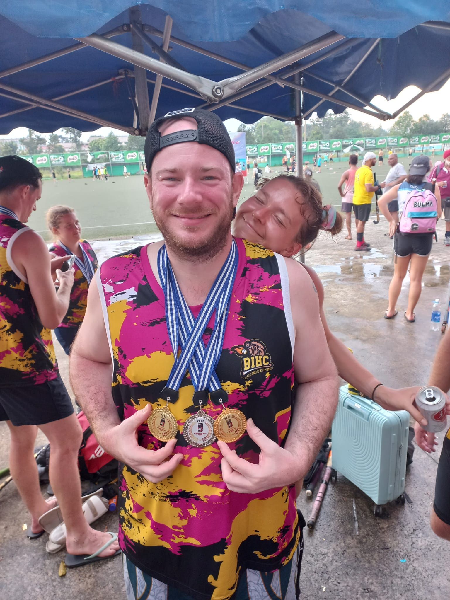 A man is holding a medal around his neck while standing next to a woman.