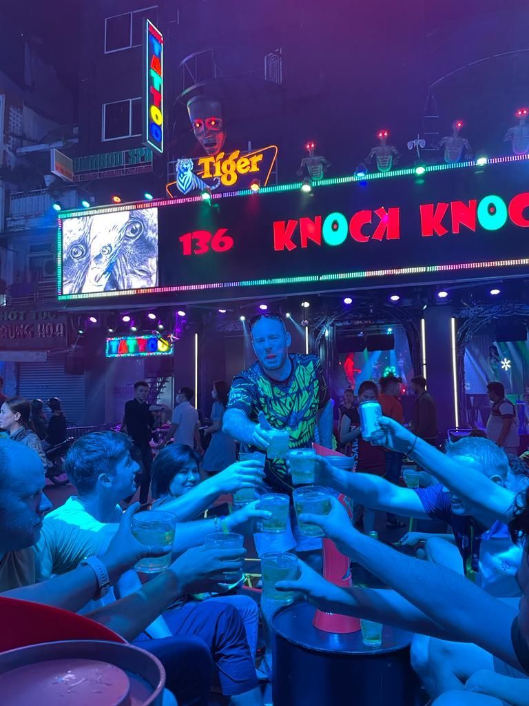 A group of people toasting in front of a sign that says knock knock