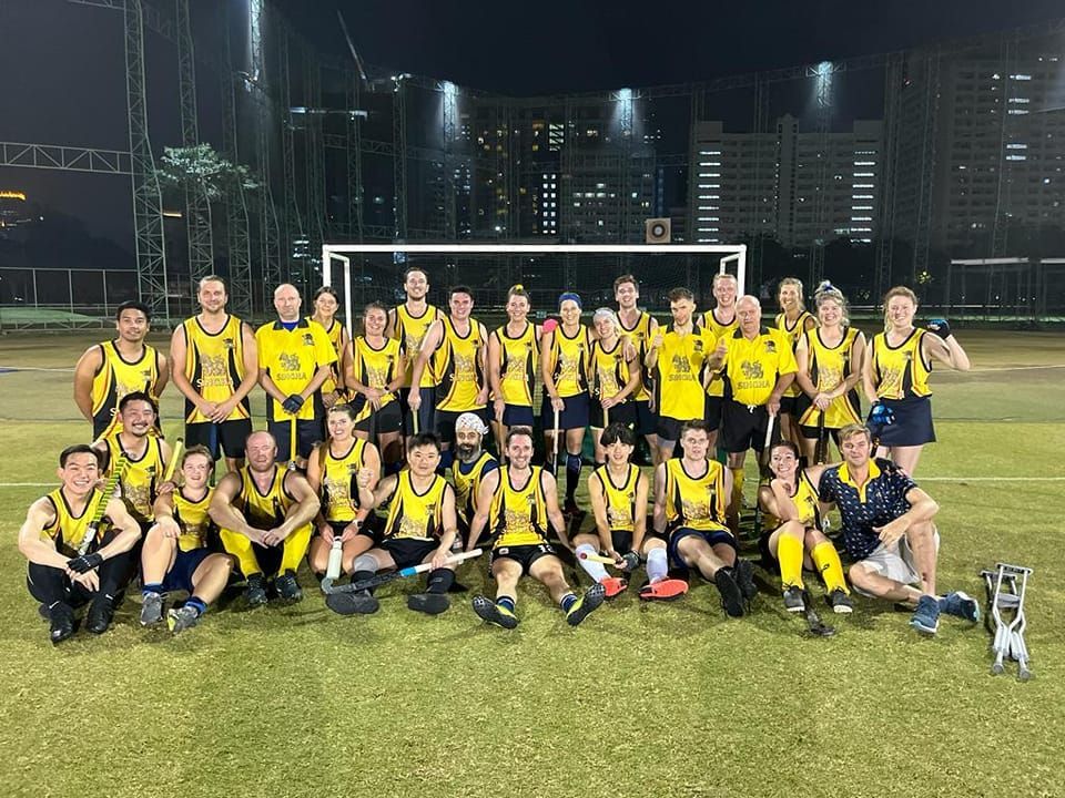A group of people are posing for a picture on a soccer field.