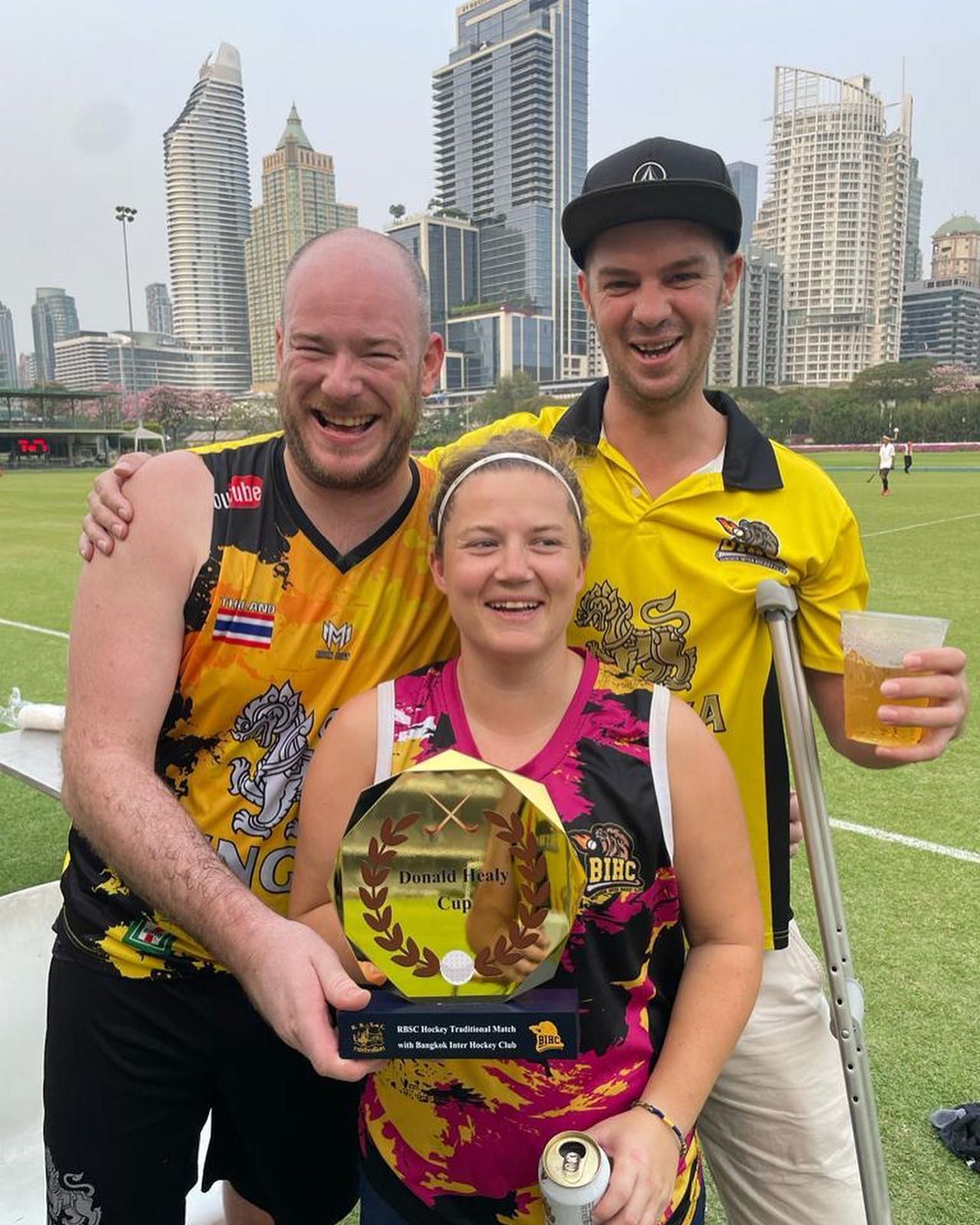Two men and a woman are posing for a picture on a field