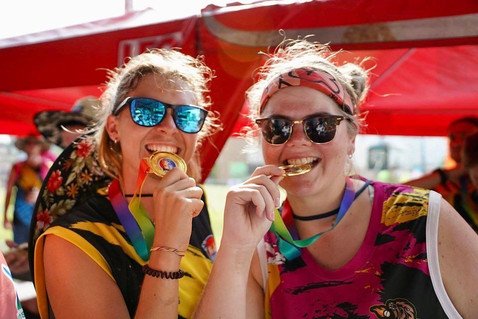 Two women wearing sunglasses and medals are eating food.
