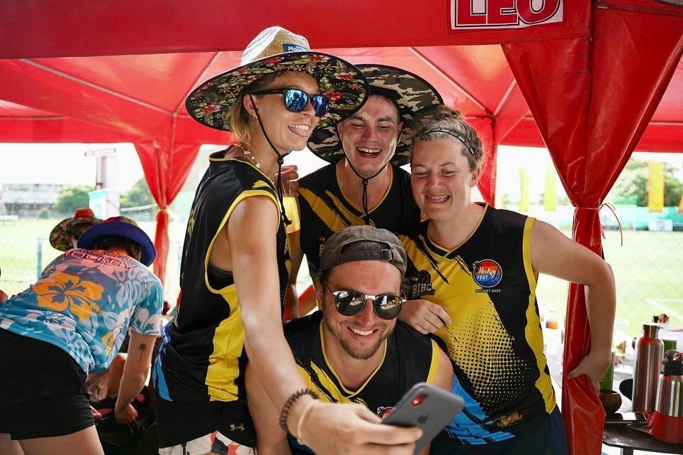 A group of people are posing for a picture under a red tent.