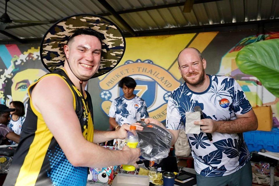 Two men are standing next to each other in front of a mural.