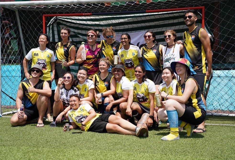 A group of people are posing for a picture on a soccer field.