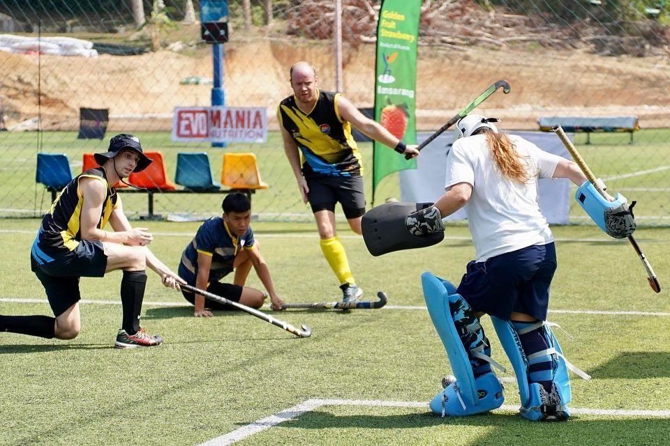 A group of men are playing a game of field hockey on a field.