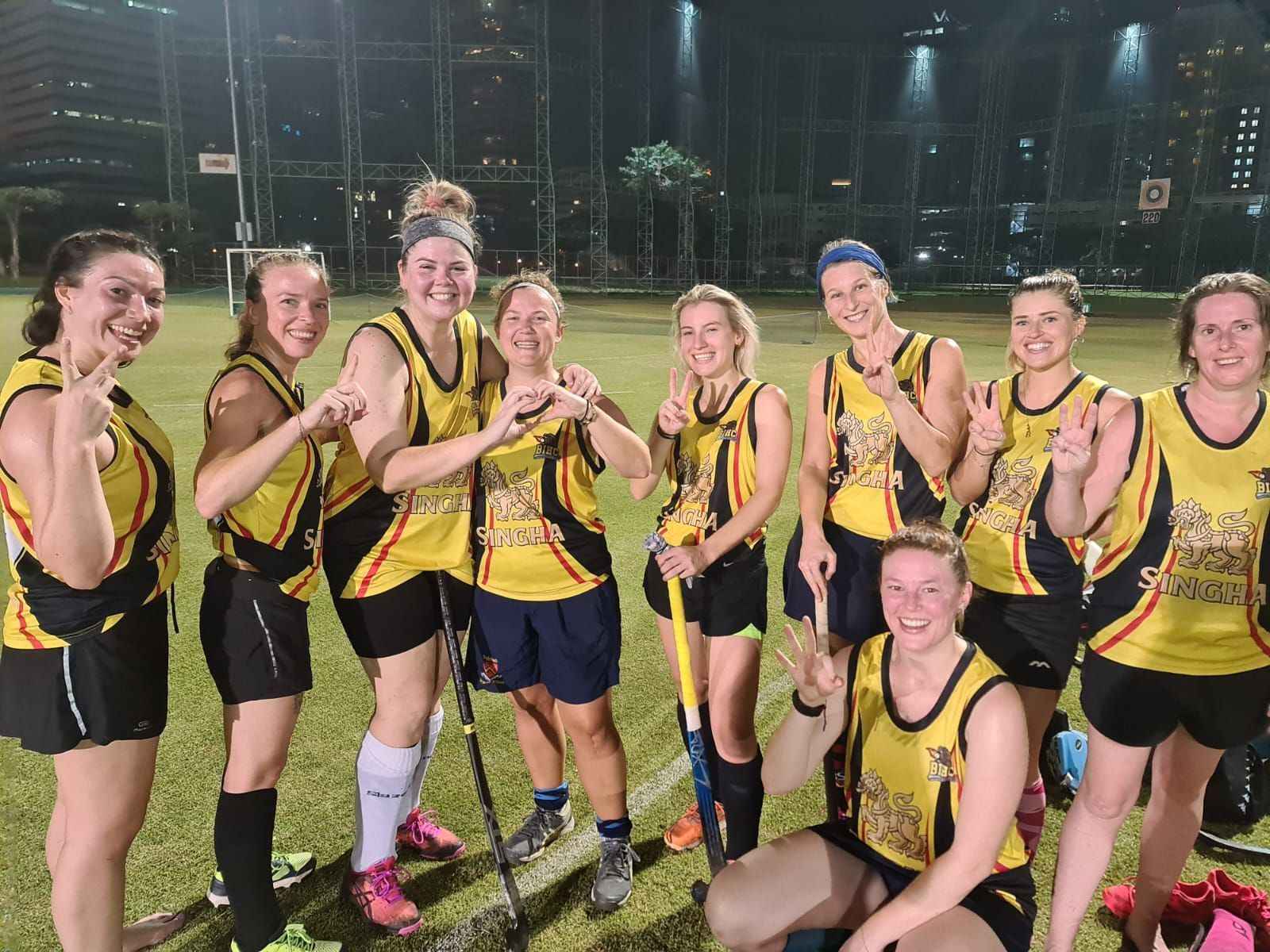 A group of women are posing for a picture on a field.