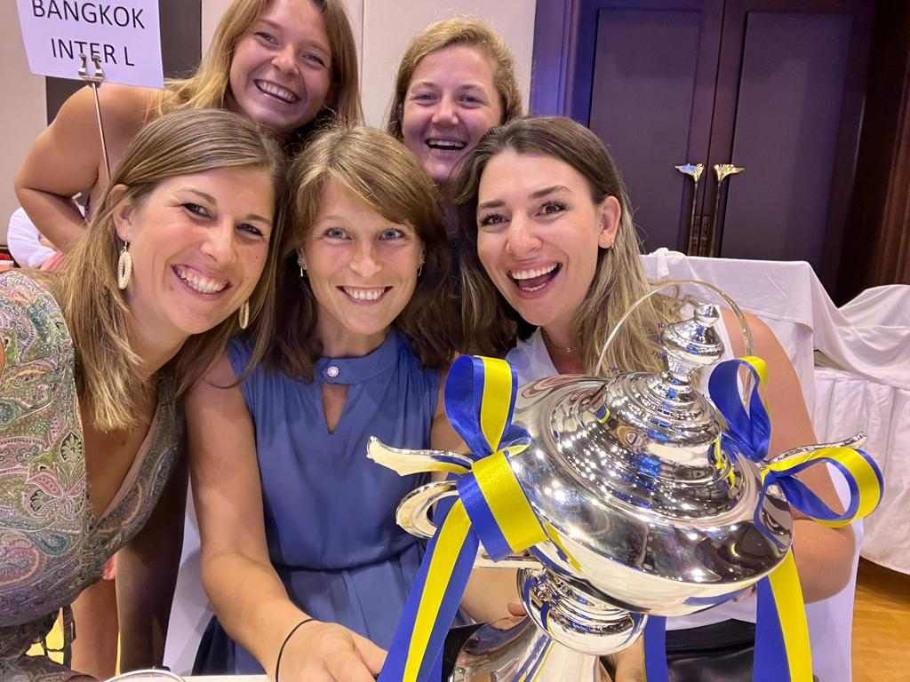 A group of women are posing for a picture with a trophy.