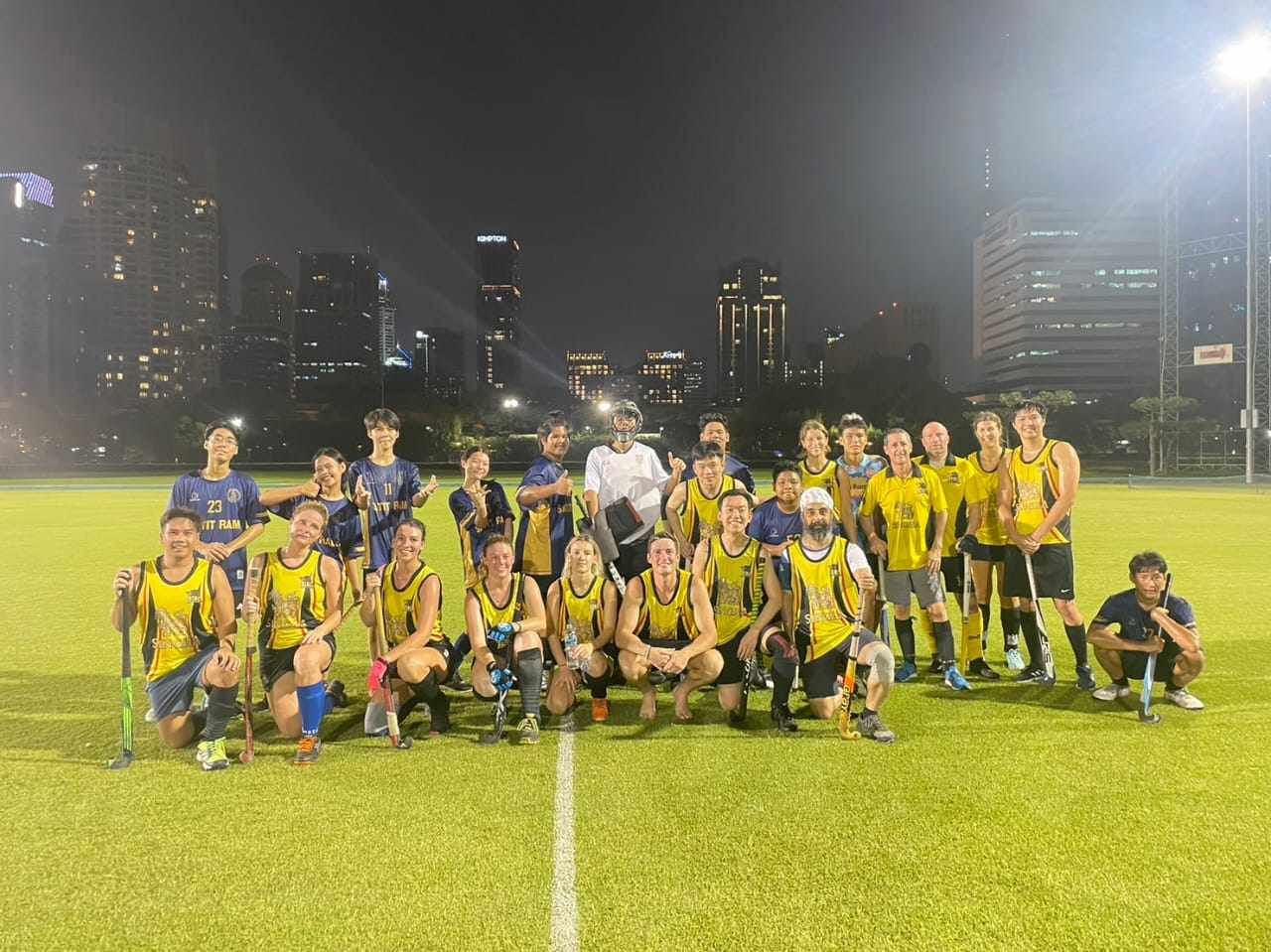 A group of people are posing for a picture on a field at night.