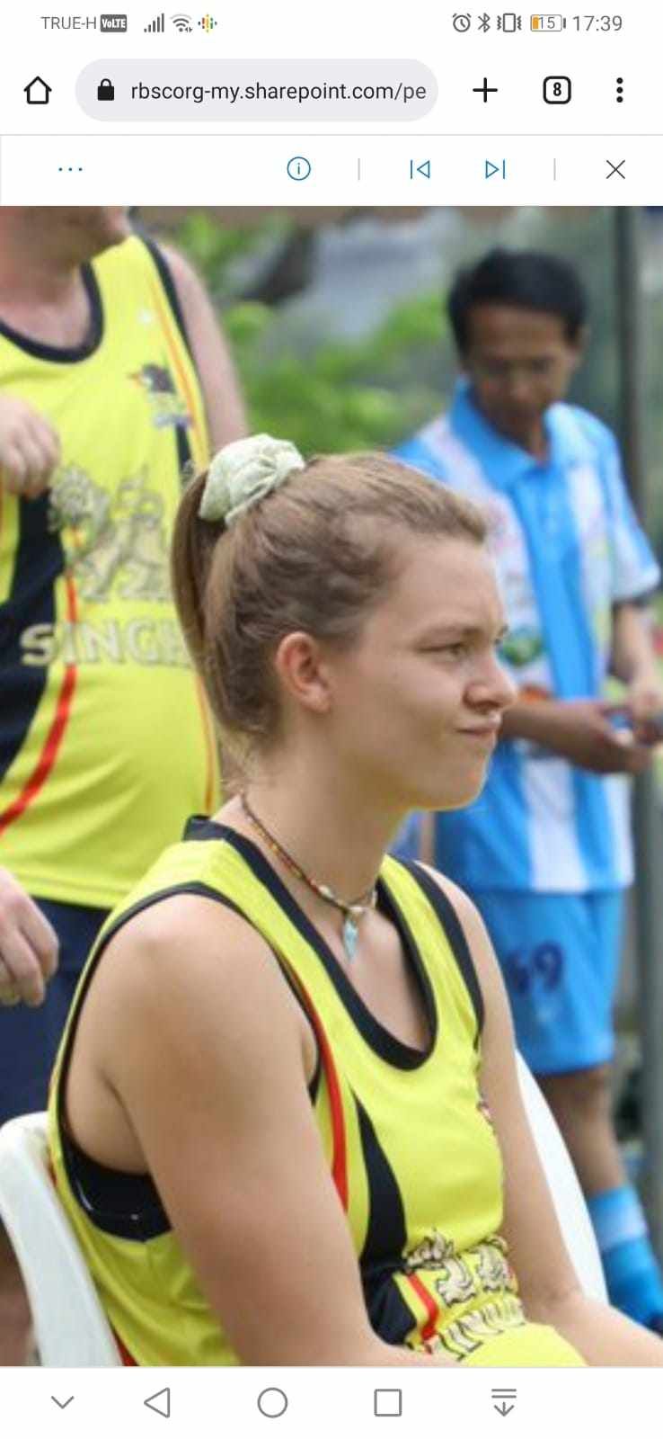 A woman in a yellow tank top is sitting in a chair.