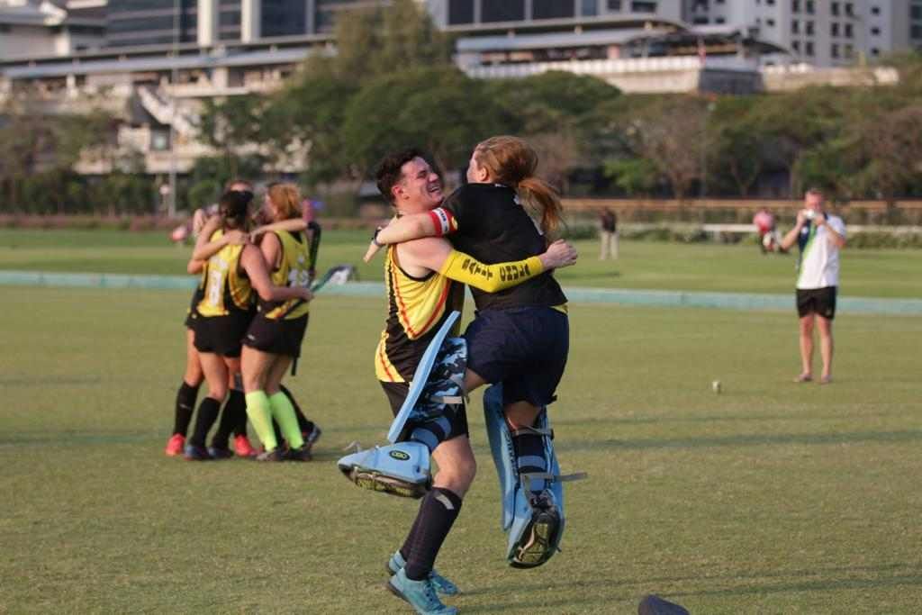 A group of people are hugging each other on a field.