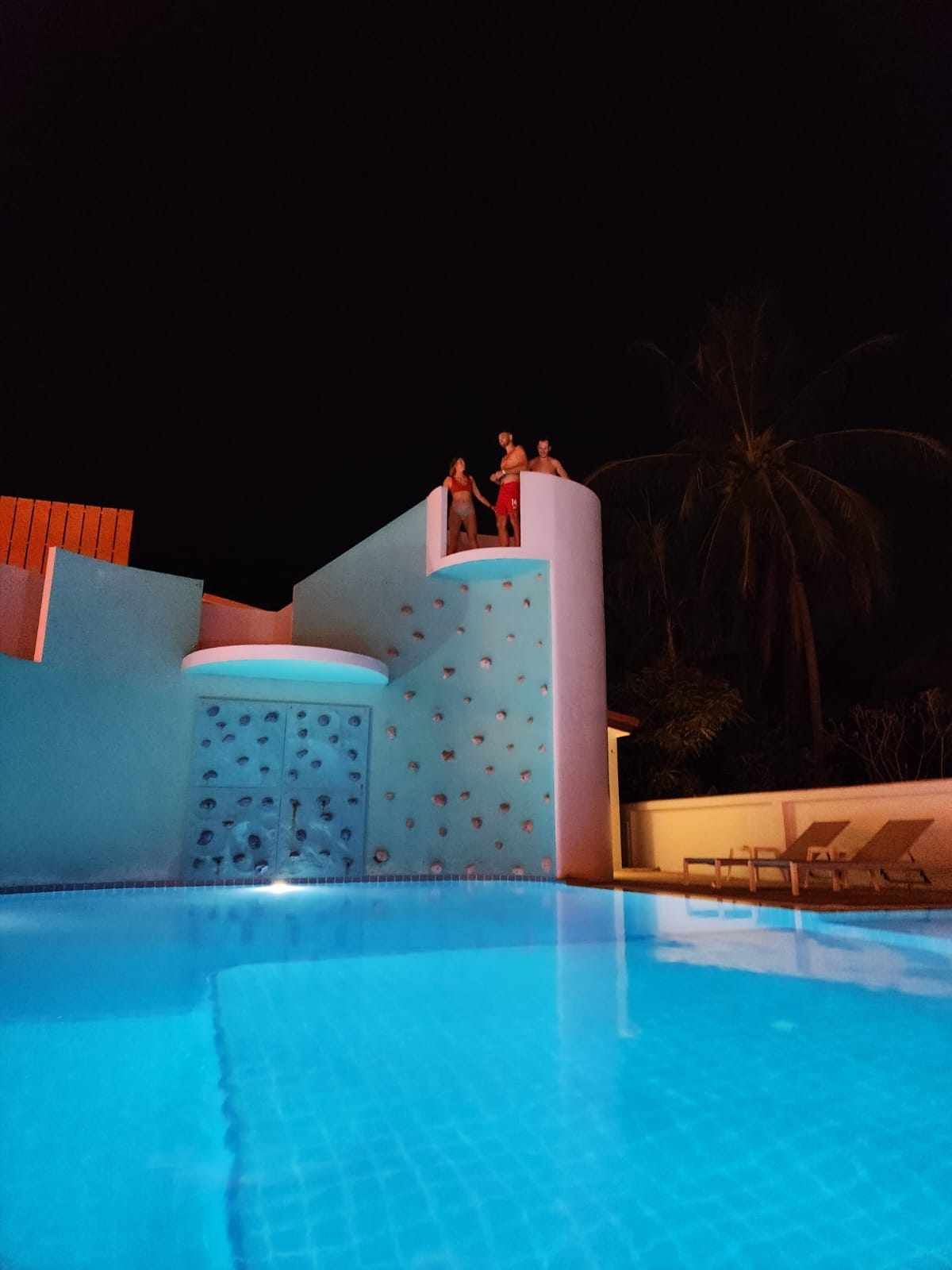 A couple of people standing on top of a swimming pool at night