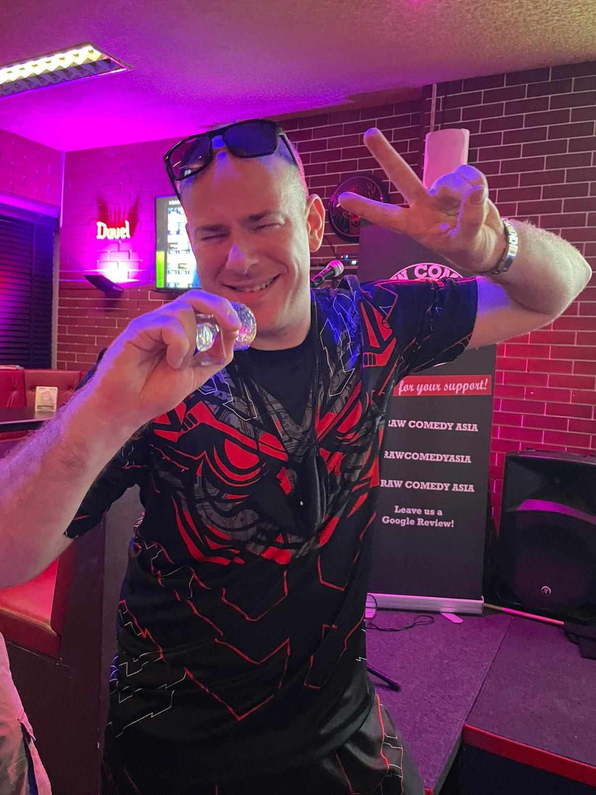 A man in a red and black shirt is giving a peace sign.