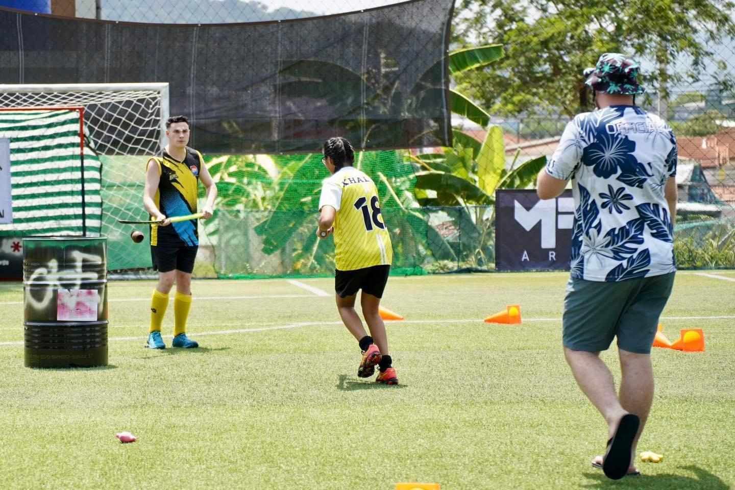A man in a floral shirt is taking a picture of a soccer game on a field.