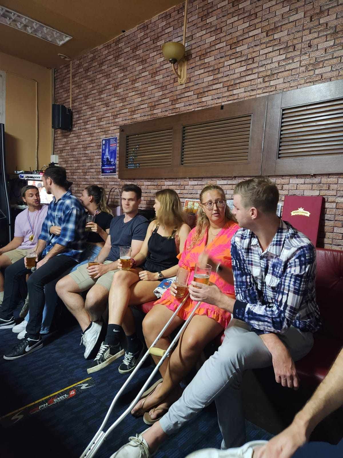 A group of people are sitting on a couch in a room with a brick wall.