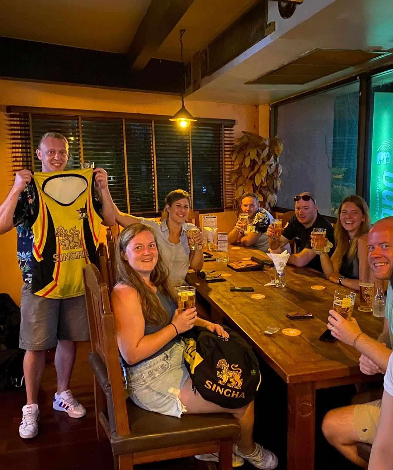 A group of people are sitting at a table drinking beer