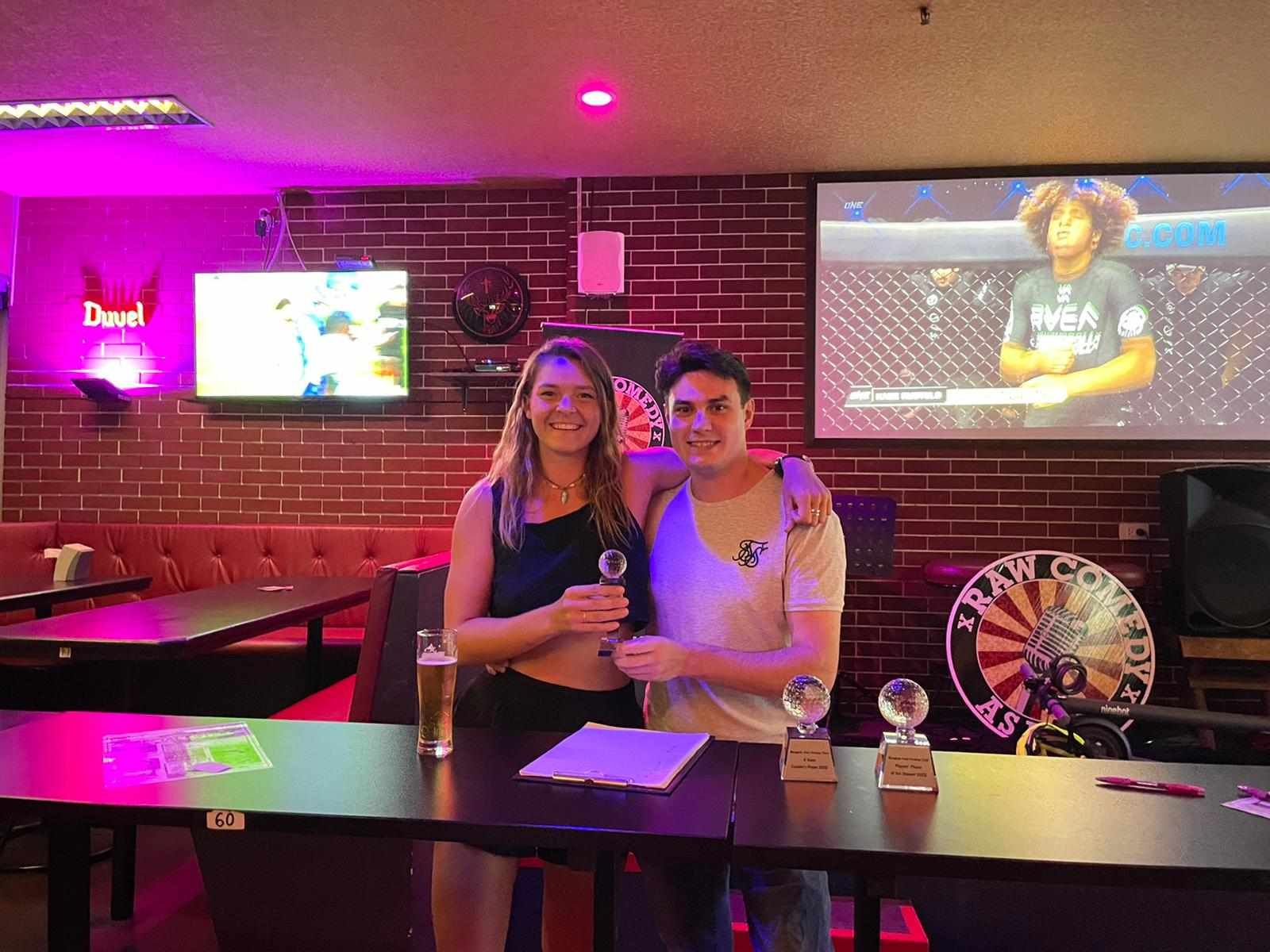 A man and a woman are posing for a picture in a bar.