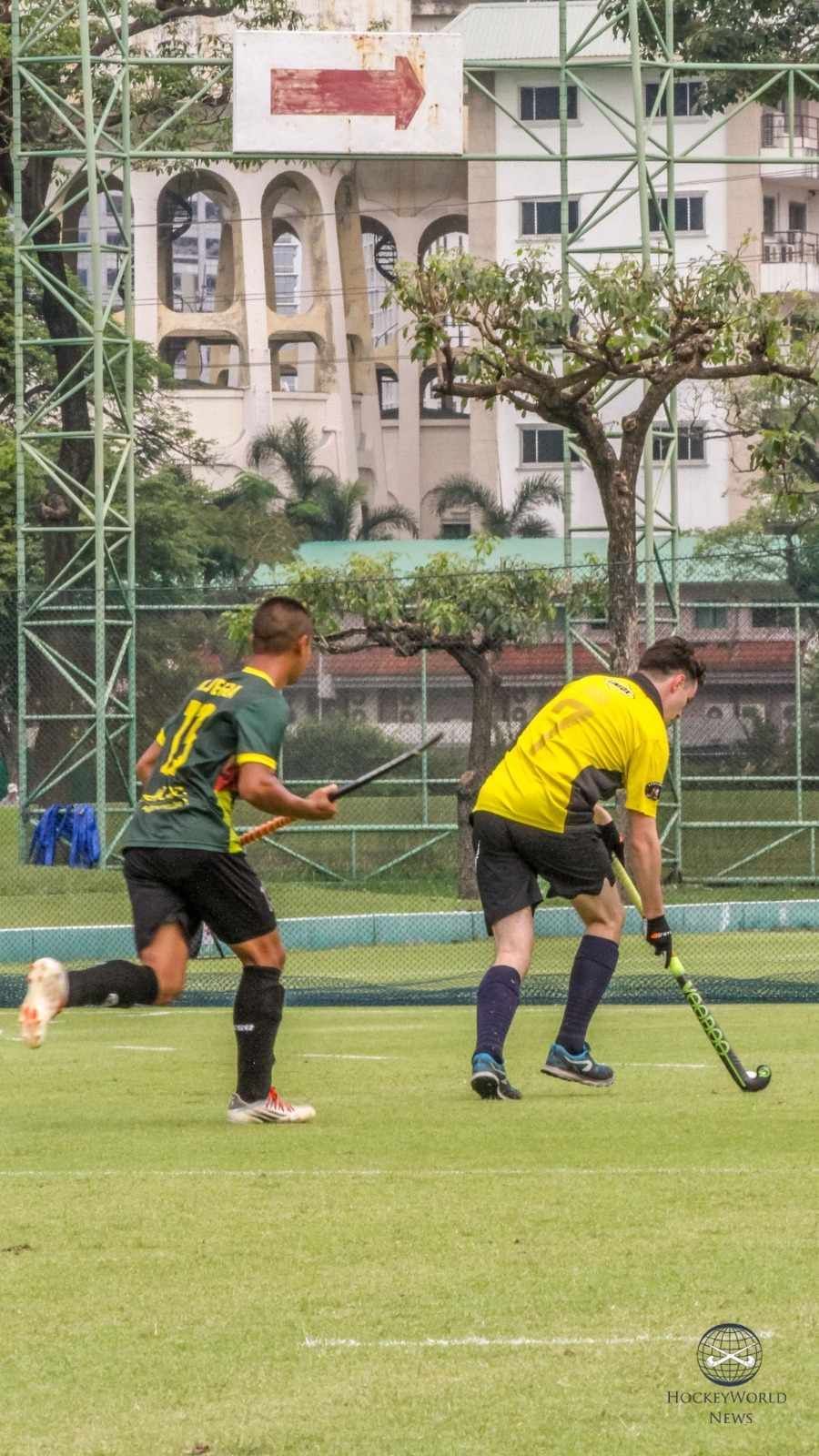 Two men are playing field hockey on a field.
