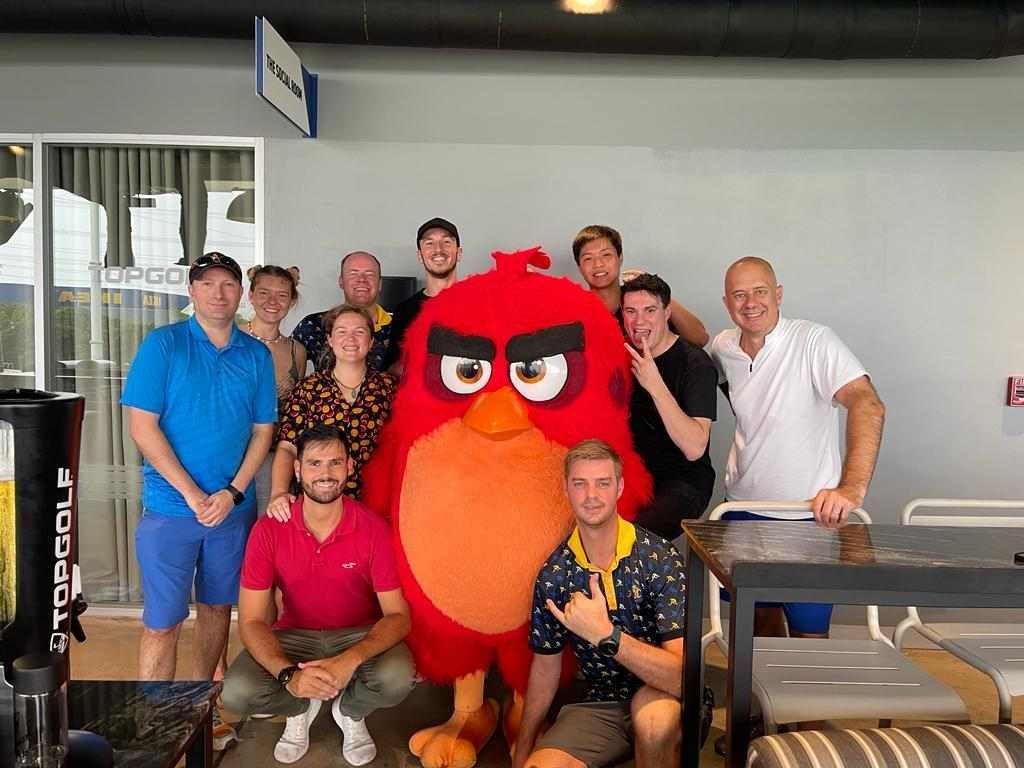 A group of people are posing for a picture with an angry bird mascot.