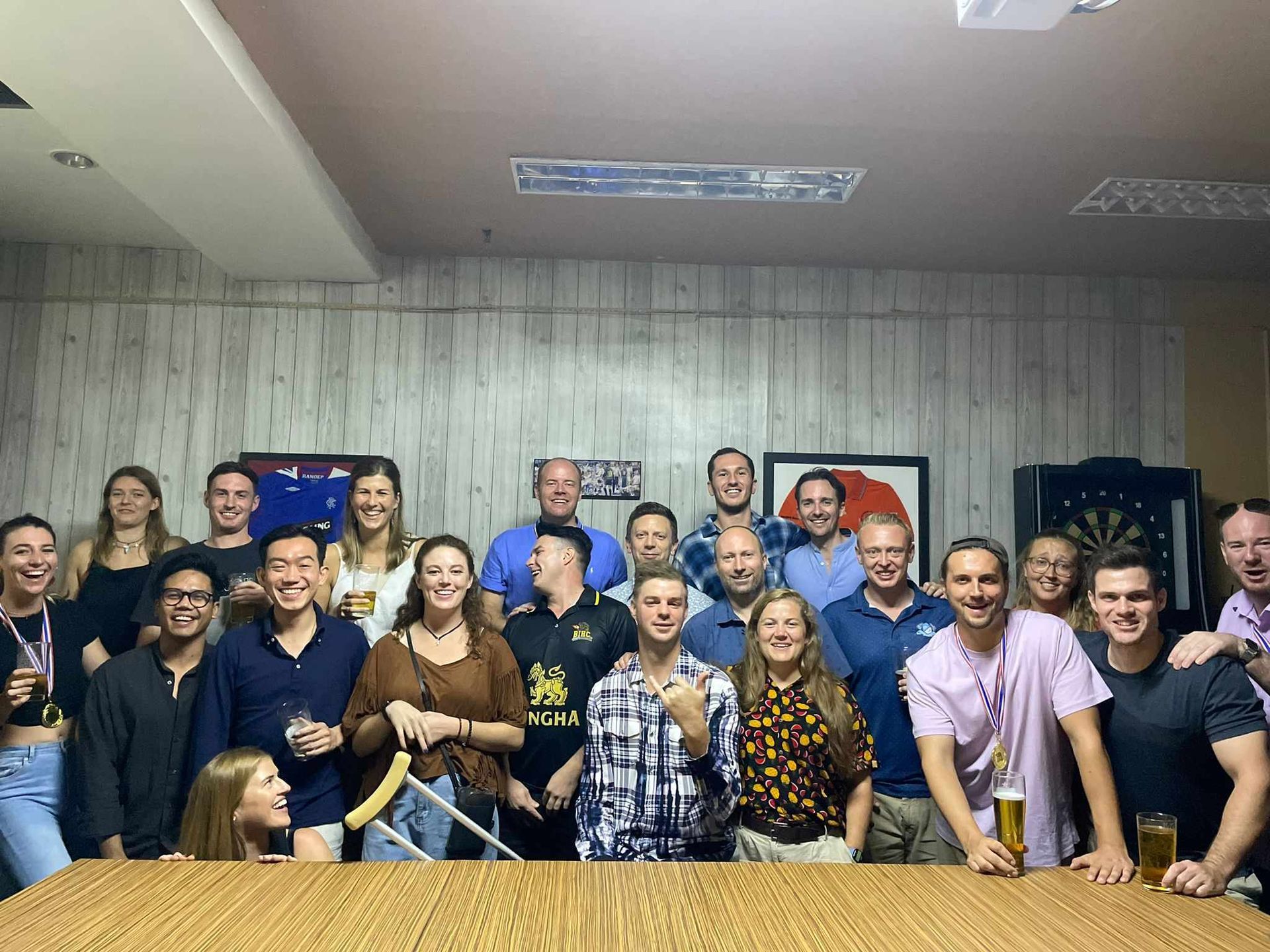 A group of people are posing for a picture in front of a pool table.