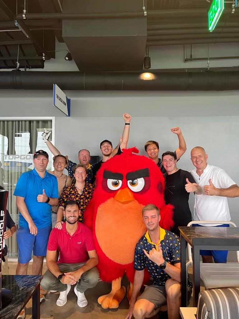 A group of people are posing for a picture with an angry bird mascot.