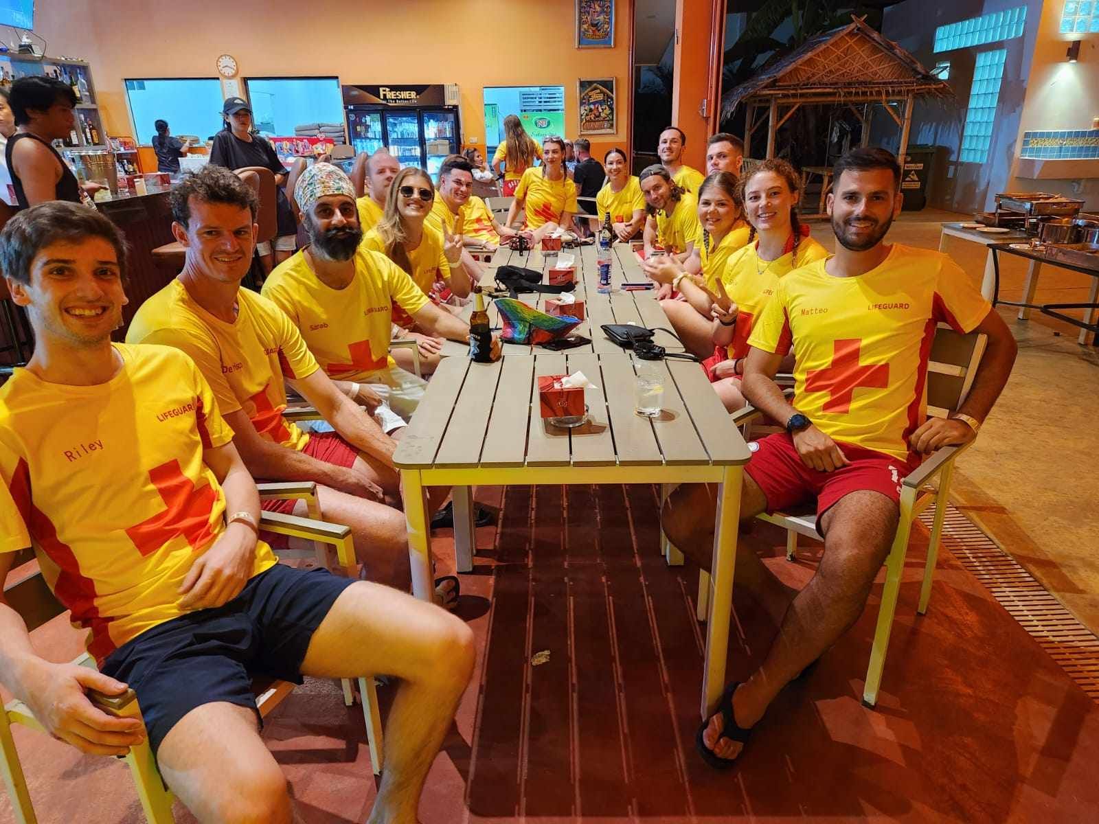 A group of people in yellow shirts are sitting around a table.