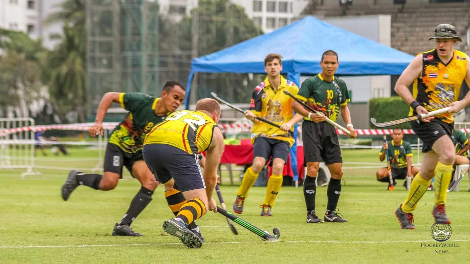 A group of men are playing field hockey on a field.
